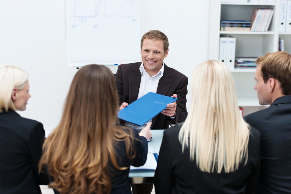 Businessman in a corporate interview handing over his curriculum vitae to one of the human resources team conducting the interview