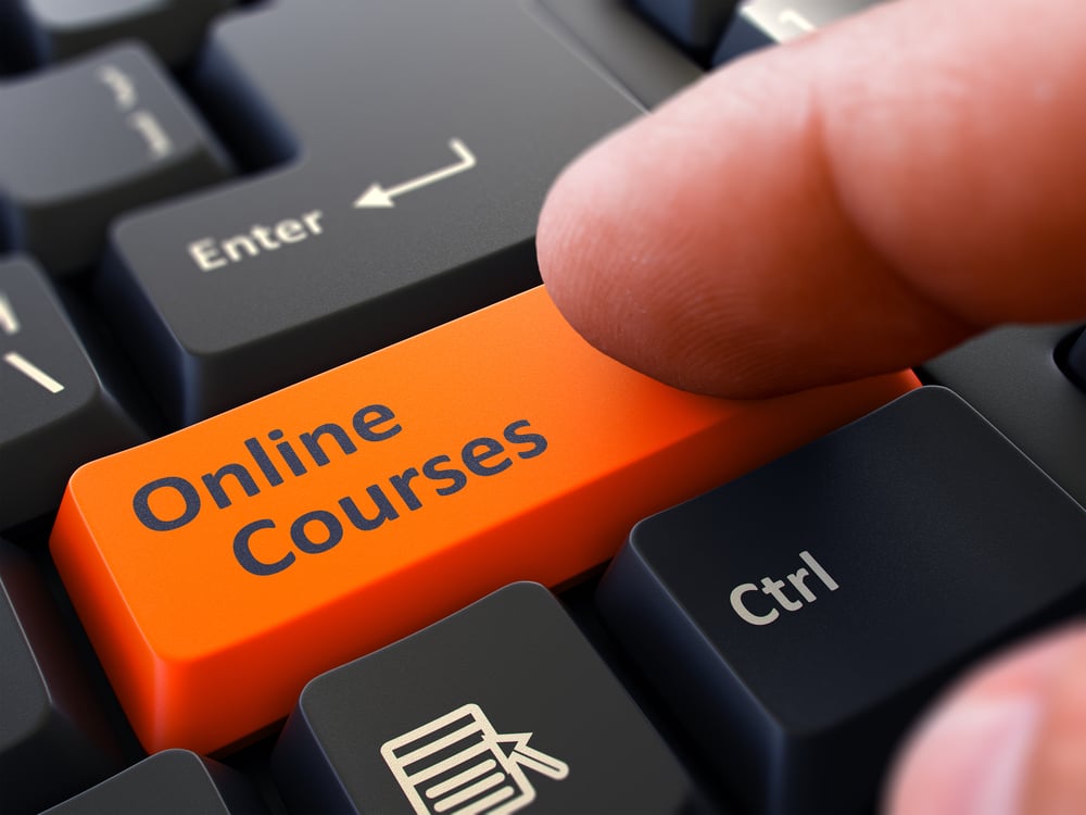 Online Courses Orange Button - Finger Pushing Button of Black Computer Keyboard. Blurred Background. Closeup View.